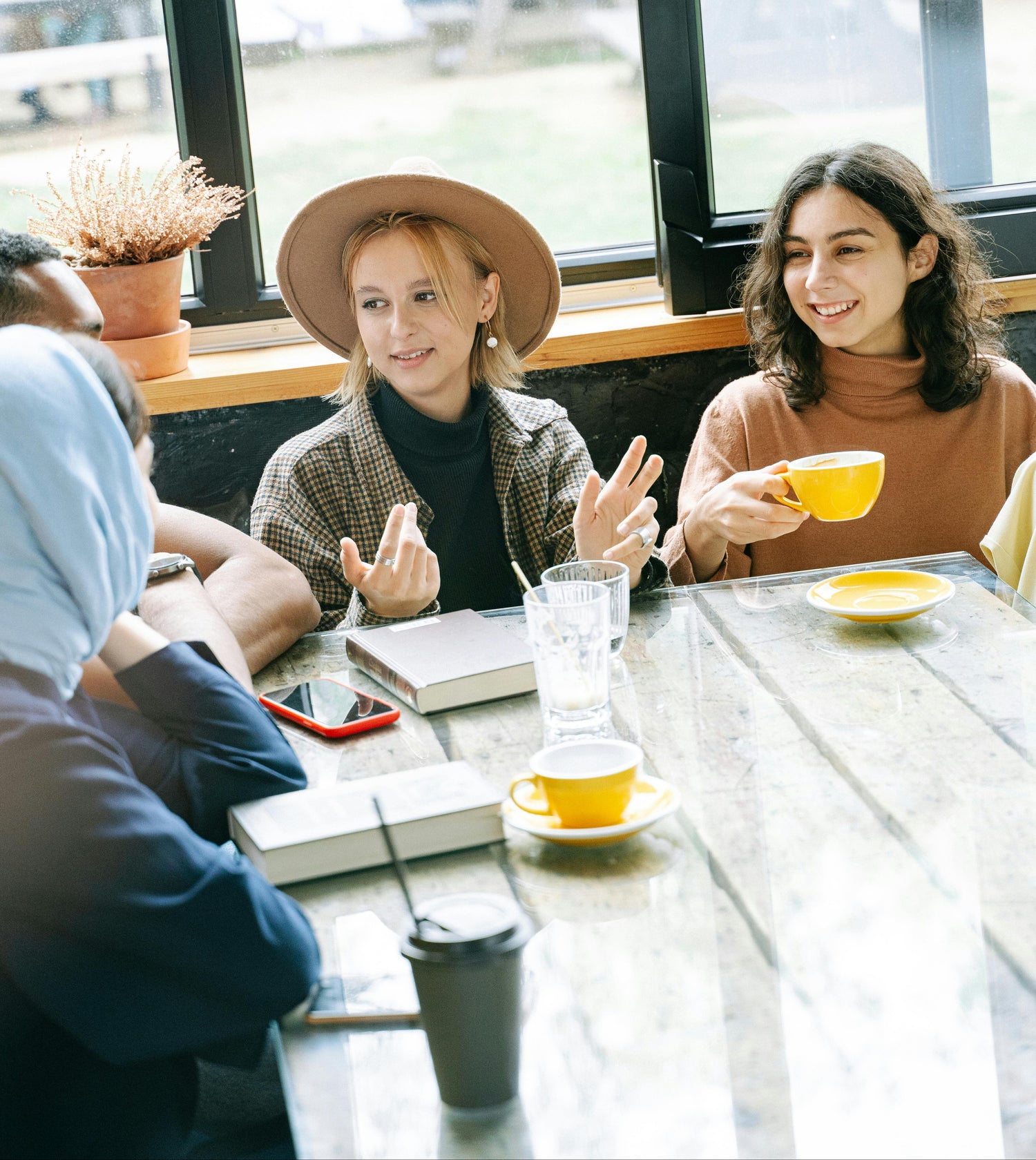 Two women sitting at a table with coffee cups, engaged in conversation.